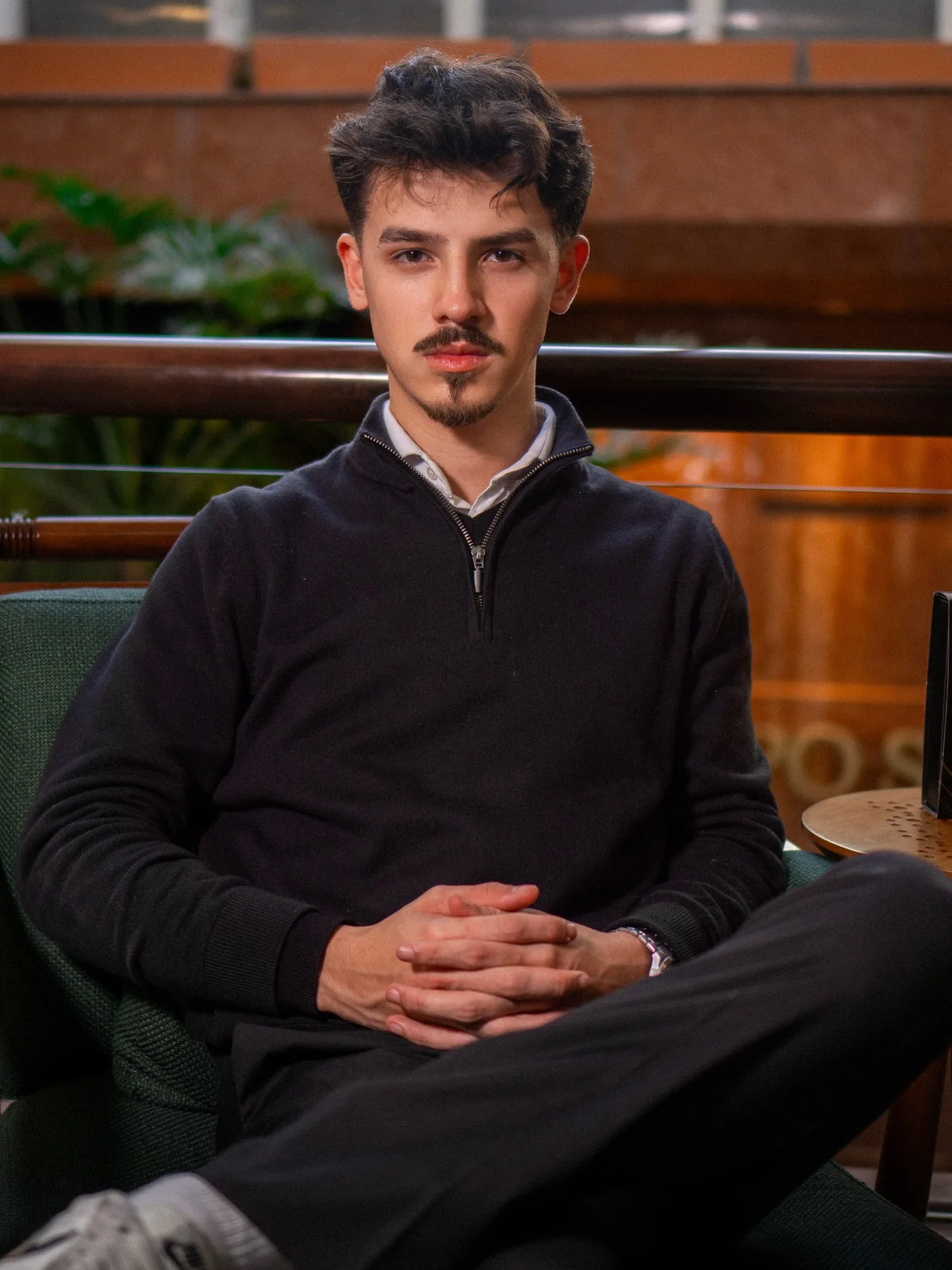 Retrato de Davi Bortoli sentado, usando camisa clara e suéter escuro